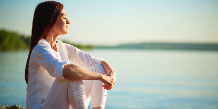 Woman meditating seaside practical mindfulness exercises