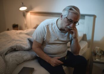 Mature man sitting in bed, wishing he knew how to fall asleep fast
