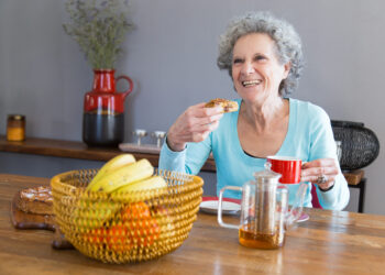 diet in old age Happy senior lady savoring dessert, emphasizing the role of dietary choices in aging and longevity.