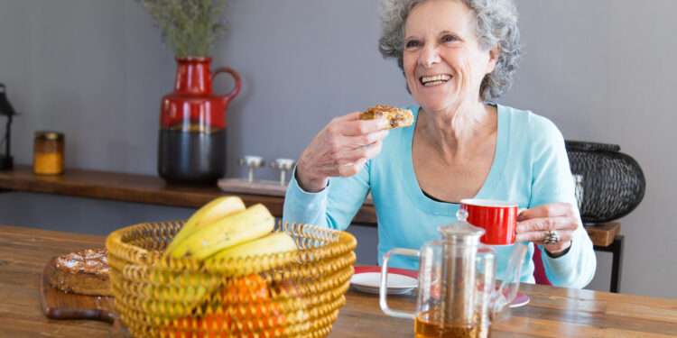 diet in old age Happy senior lady savoring dessert, emphasizing the role of dietary choices in aging and longevity.