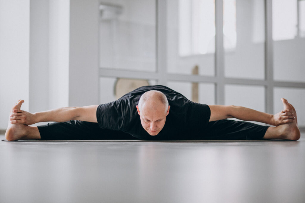Man practicing yoga in the gym demonstrating stretching benefits for flexibility and wellness