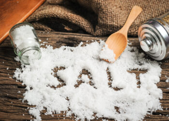Celtic salt benefits written on a heap of salt on a wooden table