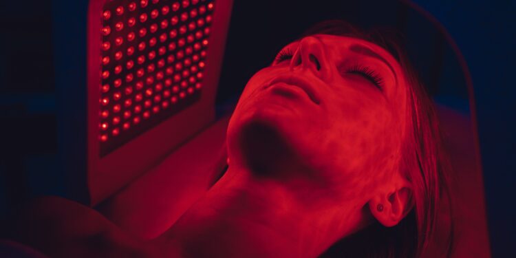 Does red light therapy work through clothes: woman receiving facial red light treatment